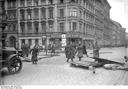 Originaltitel:Die grossen Mai-Unruhen in Berlin! Baumaterialien, welche von den Kommunisten zum Bau einer Barrikade herangeschleppt wurden, werden von der Polizei beseitigt. Im Hintergrund die auseinandergetriebenen Demonstranten. Archivtitel:Blutmai, Kämpfe zwischen Polizei und Demonstranten während kommunistischer Maidemonstrationen, trotz Demonstrationsverbotes Datierung:1. Mai 1929 Fotograf:Pahl, Georg Quelle:Bundesarchiv